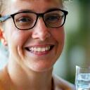 Persona sonriente bebiendo agua fresca al hacer ejercicio